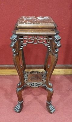 an old wooden table with a carved top on a red carpeted floor
