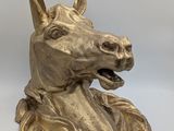 brass sculpture of a horse ' s head on a white background