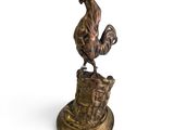 une statue représentant un coq perché sur une souche de bois