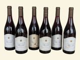 six bottles of wine are lined up in a row on a table