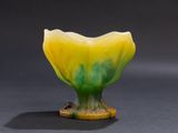 a yellow and green vase sitting on a black surface