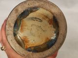 a person holding a bowl that has a brown and blue design on it