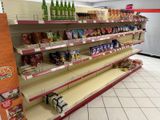 many empty shelves in a grocery store with drinks and snacks