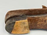 une vieille paire de chaussures marron avec un talon en bois, posée sur une surface blanche