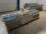 Plusieurs piles de barres d'acier sont empilées sur des palettes dans un entrepôt