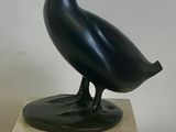 a black bird statue on a marble block on a table
