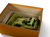 a green toy truck in a box on a white surface