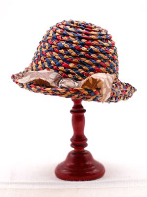 un petit chapeau posé sur un support en bois, sur fond blanc