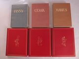 Quatre livres sont posés sur une surface blanche, avec des lettres dorées.