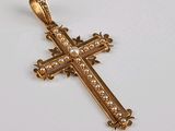 une image représentant une croix en or ornée de perles, posée sur un fond blanc