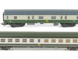 six green and white train cars are lined up on a white surface