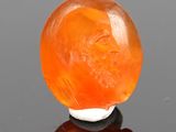 une boule de jade orange posée sur une surface noire
