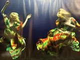 painting of two women in colorful dresses are dancing in the water