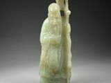 une figurine en jade vert représentant un homme tenant un bâton