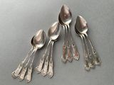 six spoons and a spoon rest on a gray surface