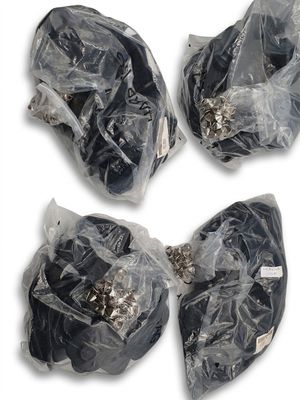 quatre morceaux de plastique noir emballés dans des sacs en plastique, posés sur une surface blanche