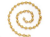 a close up of a gold beaded necklace and bracelet on a white background