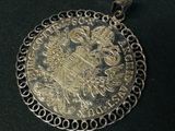 une image représentant un pendentif en argent orné d'un médaillon en or
