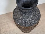 a black vase sitting on a wooden floor next to a white wall