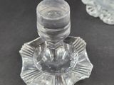 a small glass candle holder on a table next to a vase