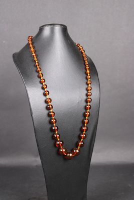 un collier composé de perles de verre orange, présenté sur un mannequin