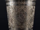 a silver cup with a floral design on the rim