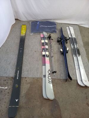 Plusieurs skis et snowboards sont alignés par terre
