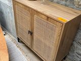 a wooden cabinet with a basket on top of it next to a table