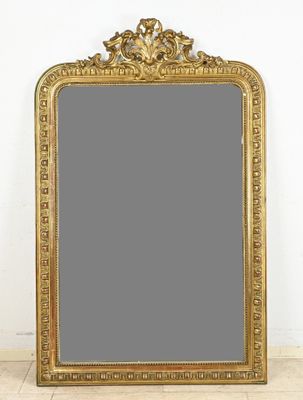 an ornate gold framed mirror on a wooden floor next to a white wall