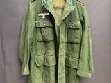 une veste vert militaire accrochée à un cintre sur un mur