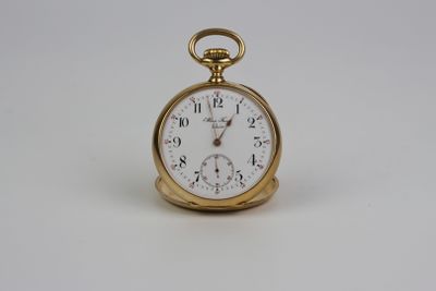 une montre de poche en or avec un cadran blanc sur une surface blanche