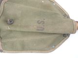 a green bag with a brown handle on a white surface