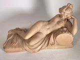 statue d'une femme allongée sur un oreiller, posée sur une surface blanche