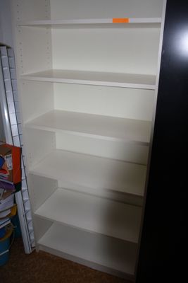 une bibliothèque blanche dans un coin de la pièce