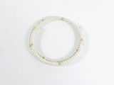 un bracelet blanc orné de perles avec des touches dorées sur fond blanc
