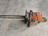an orange chainsaw sitting on the ground in a concrete area