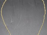 a gold necklace with blue and white beads on a black background