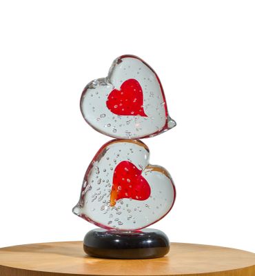 two glass hearts stacked on top of each other on a wooden stand
