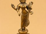 a bronze statue of a woman holding a bird on a pedestal
