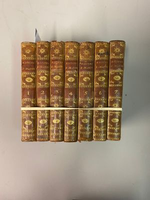 Plusieurs vieux livres sont empilés sur une étagère dans une pièce