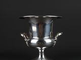 a silver vase with two hands on the base