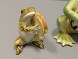 two figurines of a frog and a frog sitting on a table