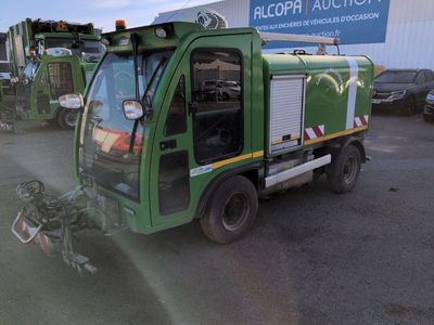 a green garbage truck parked in a parking lot