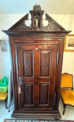 une armoire en bois munie d'une porte, avec une chaise placée devant