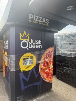 une boîte sur laquelle est représentée une pizza, devant un immeuble