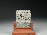 une sculpture en jade blanc représentant un lion, posée sur un socle en bois