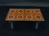 an orange and black tiled coffee table with wheels on a black background