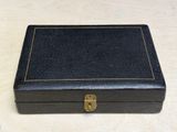 an old black leather box with a brass lock on a table