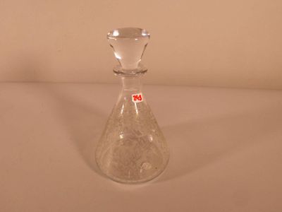 un vase en verre transparent sur lequel est collé un autocollant rouge