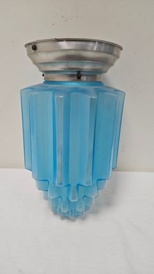 vase en verre bleu avec un couvercle argenté, posé sur une surface blanche